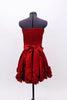 Red strapless taffeta dress has pleated front waist band & smocked back. Bottom of the dress is scalloped with rosettes.Has wide sash that  ties at the back. Back