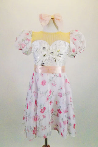 White chiffon dress with pink rose print has sweetheart neckline attached to a nude mesh upper & back. Pouf sleeves & embroidered lace front complete the look. Comes with bow hair barrette and pink satin sash. Front