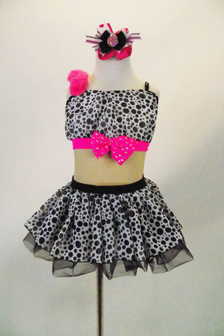 Black & white spotted chiffon dress has nude mesh mid-torso, black sequin back and bright pink band with crystal covered bow at bust & chiffon crinoline skirt. Comes with matching hair accessory. Front