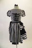 Black and white striped saloon girl themed dress has a laced bib bust area and short pouffe sleeves. The right hip is gathered with pick-ups in layers of black and black/white checkers. The back of the dress has lace-up detail. Comes with matching hair accessory. Back