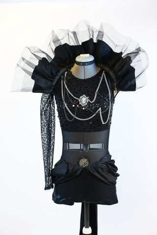 Black sequined bodice with single sleeve, adorned with silver and black chains and a large cameo. Leathery shorts with sash and removable large tulle collar, front