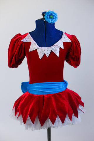 Red velvet dress with jagged edges on white petticoat skirt. Has jagged collar & large turquoise waist sash. Comes with a matching turquoise floral hair piece. Front zoomed