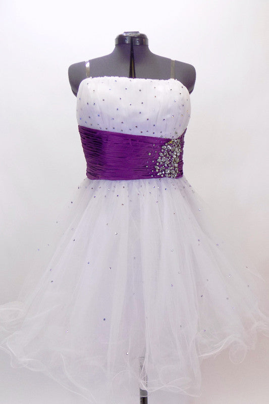 White curly edge tulle boned dress has ruched purple satin waist band with large jewel accents. There is scattered amethyst Swarovski crystals throughout dress. Front