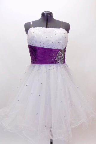 White curly edge tulle boned dress has ruched purple satin waist band with large jewel accents. There is scattered amethyst Swarovski crystals throughout dress. Front
