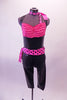 Black shiny halter leotard has a pink finely ruffled bust area. It is accompanied by black Capri leggings with a polka dot bow tie-up waistband. The matching polka dot knee-length skirt goes over the pants. Comes with matching neck scarf. Front with Capri pants