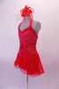 Red short dress has red sheer back, round cut sides and peek-a-boo center. The bust is gathered and covered with scattered crystals. All the banding is sequined red and the sheer red skirt and wide curly binding for large curled effect. Comes with red fascinator hat/headband accessory with a birdcage veil. Side
