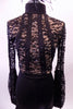 Black lace short unitard has a solid bottom. The lace front & long lace bishop sleeves have 4 vertical solid stripes that extend from the high collar to the waistline at an angle. The large open keyhole back has 4 narrow vertical bands. All the edging is lined with crystals  Comes with black feathered hair accessory. Front zoomed