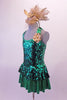 Green sequined peplum dress has shimmery green skirt below the peplum that matched the banding of the halter collar and large bow at the back of the neck. The removable gold accent flower compliments the large gold fascinator headband accessory. Left side