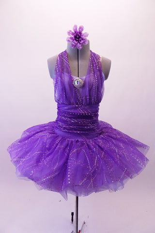 Purple tutu has more contemporary styling with a halter overlay neck on the camisole bodice with large crystal Brooch accent. The wide gathered cummerbund waistband, front -halter & skirt of the dress are sheer poly-chiffon with streaks of silver dot veining. The back of the bodice is pale lavender. Front