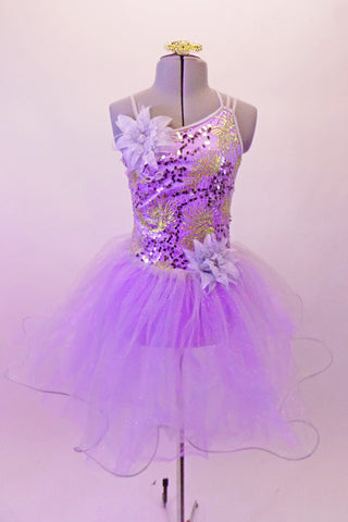 Lavender romantic tutu has a glitter tulle skirt with large curly hem. The bodice has gold and purple sequined accents with a single right and triple left shoulder strap that form a unique angle at the back. There is a large lavender flower accent at the right shoulder and left hip. Comes with a gold hair barrette. Front