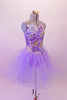 Lavender romantic tutu has a glitter tulle skirt with large curly hem. The bodice has gold and purple sequined accents with a single right and triple left shoulder strap that form a unique angle at the back. There is a large lavender flower accent at the right shoulder and left hip. Comes with a gold hair barrette. Right side