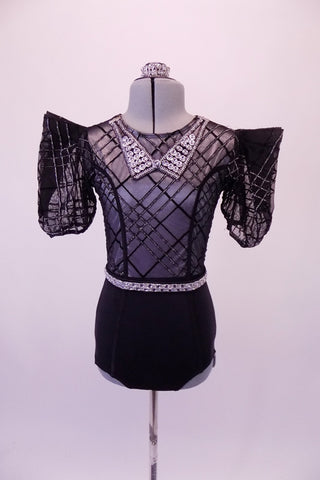 Costume is a leotard base with black brief style bottom. The bodice is a silver tank style with a black sheer overlay that has angled lines of silver & black. The pouffe style, crisp short sleeves have looping pleats for sharp-edged shoulders. The jewelled waistband & collar and some bling. Comes with a hair accessory. Front