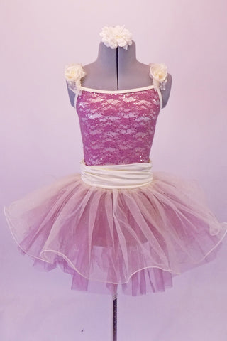 Romantic tutu dress is a cream base with sequined magenta lace overlay. The cream piping and gathered cummerbund waist complement the soft flowers at the shoulders. A cream curly hemmed cream overlay rest over the top of the magenta tulle skirt. Comes with a cream floral hair accessory. Front