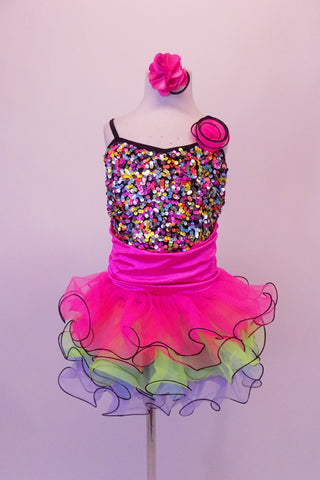 Rainbow sequined camisole tank dress has black cross straps. The curly ruffled skirt is layers of bright pink, blue and green with a black edge. There is an organza rose at the left bust. Comes with a pink floral hair accessory. Front