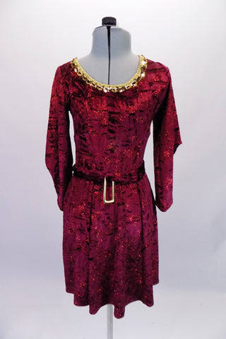 Burgundy crushed velvet, A-line tunic dress has glitter floral detail in the fabric and gold sequined braid that sits along the neckline. The ¾ angel-sleeve gives the dress a medieval look. Comes with tie belt and hair accessory. Front
