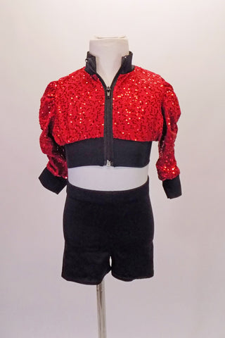 Bright red sequined crop cut jacket has black banding, and ¾ gathered sleeves. Matching black shorts accompany the jacket. Front