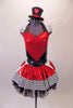 Halter style leotard dress has a large red heart front over a back base with ruffled organza collar. The attached skirt is shiny red with a black & white houndstooth edge over the top of black tulle. Two large white & red heart panels accent each of the hips. Comes with a mini black top hat with a heart accent.  Front