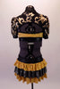 Black & gold leotard has a gold sequined floral leaf pattern along the front of the torso. Beneath is a gold sequined bra with black banding. The gold sequined brief has an attached bustle skirt with layers of sequined gold & black ruffles. The back is open revealing the bra & creates the appearance of a shrug. Back