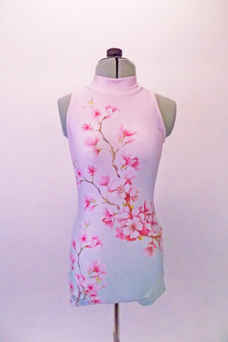 Short halter style unitard with high collar and open back has a cherry blossom pattern that cascades from the right shoulder to the left hip in a soft shade of blush pink and mint green. Front