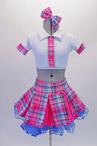 School uniform themed  2-piece costume comes with a wide pleated pink & blue tartan skirt with a wide waistband & bright pink inner pleats. The matching white half top has collar, buttons & cap sleeves with AB crystals and tartan accents. Comes with a large tartan bow hair accessory & purple gauntlets. Front