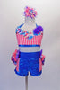 Two-piece costume comes with bright blue metallic shorts with coral check sides. The short has a 3-layered bustle of ruffles in bright colours. The halter top is coral check with floral accent, purple flower and crystal accents. Comes with a large matching hair accessory and matching gauntlets. Front