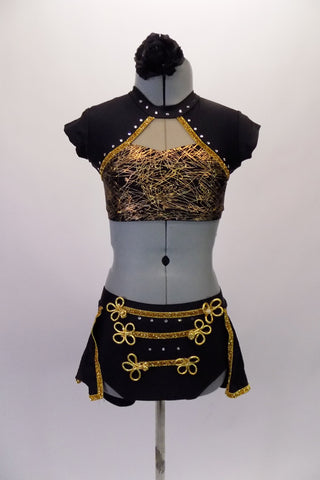 2-piece costume has a Michael Jackson flare. The gold & black sweetheart cut half top has an attached shrug like shoulder & neck in black with gold trim & crystal accents. The bottom is a brief with open front bustle. The brief has gold braided frog closure appliques & crystals. Comes with a floral hair accessory. Front