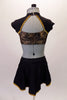 2-piece costume has a Michael Jackson flare. The gold & black sweetheart cut half top has an attached shrug like shoulder & neck in black with gold trim & crystal accents. The bottom is a brief with open front bustle. The brief has gold braided frog closure appliques & crystals. Comes with a floral hair accessory. Back