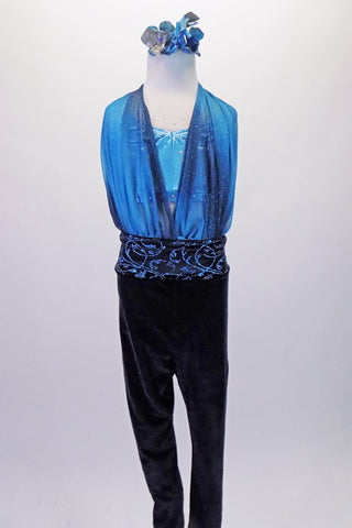 Full unitard has a blue metallic halter bra top beneath a shawled halter with black velvet bottom. The gathered shawls are attached at the centre of the waistband of the black velvet leggings and come up over the bust on either side clipping at the back of the neck. Comes with a blue floral hair accessory. Front