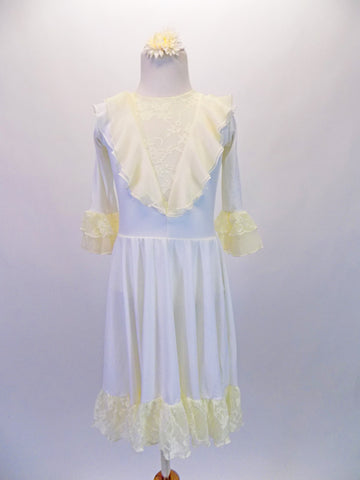 Ivory knee-length dress has buttercream yellow, deep V front, lace inlay edged with a soft double chiffon ruffle also mirrored on the back with a keyhole opening. The long sleeves have a double lace ruffle, that compliments the wide lace ruffle on the edge of the skirt. Comes with an ivory floral hair accessory. Front