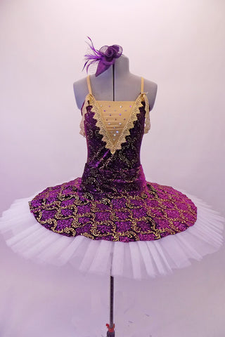 Tutu has a deep purple velvet base with gold brocade design. The bodice has a lined, nude V-front bust area with crystal accents & gold crochet lace edging that extends to form draping shoulder loops. The back has cross straps for support. The overlay skirt with attached basque sits over top of the white pull-on tutu. Front
