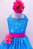Sparkle- lycra turquoise halter dress has bright pink crystal covered waistband with pink flower and matching bottoms. Comes with matching pink floral hair accessory. Front zoom