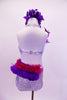 White sequined halter leotard has large crystal sequined appliques along left front bodice. Purple feathers and a hot pink ruffle cover from the left hip around the back.  There is a purple sequined and feather accest in the right shoulder. Comes with purple feather hair accessory. Back