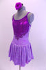 Pale lavender marble  leotard dress has purple glitter front bodice and low open back with cross straps.  A purple glitter swirled applique accent surrounds the glittery bodice. Comes with matching hair accessory. Left side
