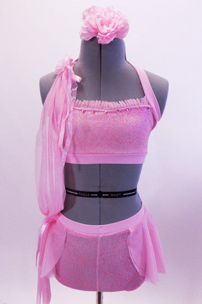 Pink sparkle fabric half-top with ruffle accent has matching shorts with light mesh skirt. The two pieces are attached along the right side with pink sheer mesh and ribbons. Waistband and bodice are accented with crystals. Comes with matching hair accessory. Front