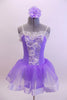 Pale lavender leotard dress has white ribbon rose detailed front bodice. The attached skirt is lavender organza that sits on layers of white tulle.  Comes with matching hair accessory. Front