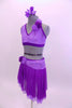 Two piece costume comes with purple sequined lace halter half top. The back has crystal covered straps with crystal ring accent.  The skirt has layers of darker purple mesh with lighter matching lace accent around hip. Both pieces have lace rose accents on left shoulder and right hip. Comes with floral hair accessory. Left side.