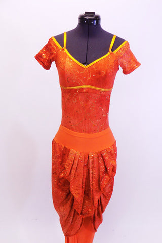Cap sleeved leotard has open lower back  and low scoop neck with bra-like closure. The orange and gold swirl marble print is accented by gold shoulder straps and piping accent. The matching harem pant has attached pleated draping at both front and back. Comes with matching hair accessory Front