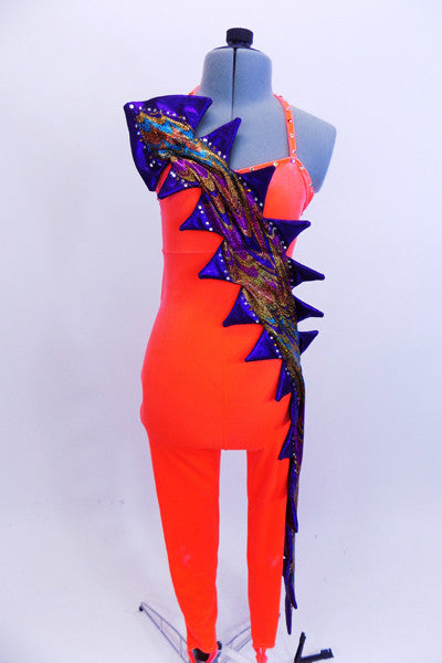 Bright orange velvet unitard has an intricate iridescent blue-purple-aqua dragon tale cascading from right shoulder across the front torso and down the entire left leg. The low open back has a series of crystal covered criss-cross straps. Front