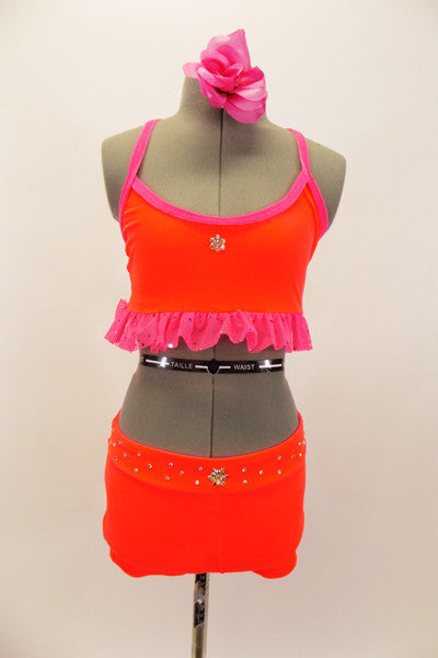 Bright neon orange/coral velvet 2 piece costume has bright pink sparkle ruffle along base of the top. The shorts have crystal accents. Very bright on stage. Comes with pink hair accessory. Front