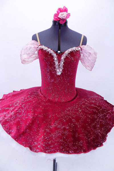 Deep cherry red velvet 10-layer white pleated platter tutu has attached ruffled panty. The velvet overlay and bodice has pink and silver branch design in the fabric. The sweetheart neckline has white lace trim with tiny rose accents and gathered chiffon shoulder drapes. Comes with matching floral hair accessory. Front