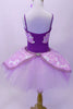 White pull on English-style tutu has layers of crisp white tulle with layers of soft  lavender tulle on top, The figure-8 overlay is a brocade pattern in lavender and white with corded trim and large broach accent at front and back. The separate purple leotard has gathered front accent and matching sequin lined brocade inserts at front and back-sides. Comes with matching floral hair accessory. Back