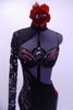 Unique black full unitard has hand painted red and silver swirls along right side and bra. The right leg is black lace down the side, while the left leg is open with rungs of red bands along the length. The right sleeve and shoulder are lace and extent to a high neck collar that reveals the bra. Comes with red and silver rose hair accessory. Front zoomed