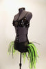 Costume has black large sequined bra top with broach. Black bottom has bustle skirt of multiple layers of green and black mesh tubes. Comes with hair accessory. Left Side