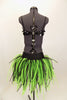 Costume has black large sequined bra top with broach. Black bottom has bustle skirt of multiple layers of green and black mesh tubes. Comes with hair accessory. Back