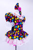 Black leotard dress has colorful puzzle piece decorative front with lace trim at neck sleeves and skirt. Dress has bright pink petticoat and matching bow hair accessory. Right side