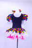 Black leotard dress has colorful puzzle piece decorative front with lace trim at neck sleeves and skirt. Dress has bright pink petticoat and matching bow hair accessory. Back