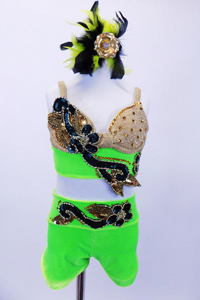 Bright green two-piece costume has gold bra with wide green band that is adorned with large jeweled green and gold appliques and gold crystals. The matching appliques extend to the shorts at both front and back. Comes with matching gold and feather hair accessory. Front