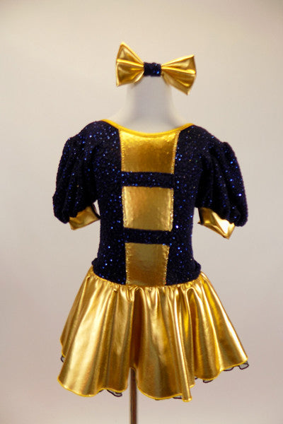 Navy blue crinkle lace dress has pouf sleeves with gold cuffs & gold striped inserts down front center of torso. Has attached gold skirt & matching hair bow. Front