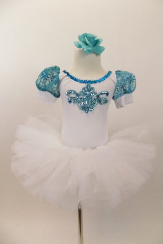 White velvet leotard has turquoise lace sleeves. Neckline has turquoise sequins & large jeweled applique. Comes with white tutu skirt & floral hair accessory. Front