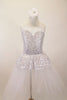 White and silver sequined romantic tutu dress has sweetheart neck-like peplum that sits on top of the long white soft tulle layers. The dress has double straps which cross at back. Comes with hair accessory. Front